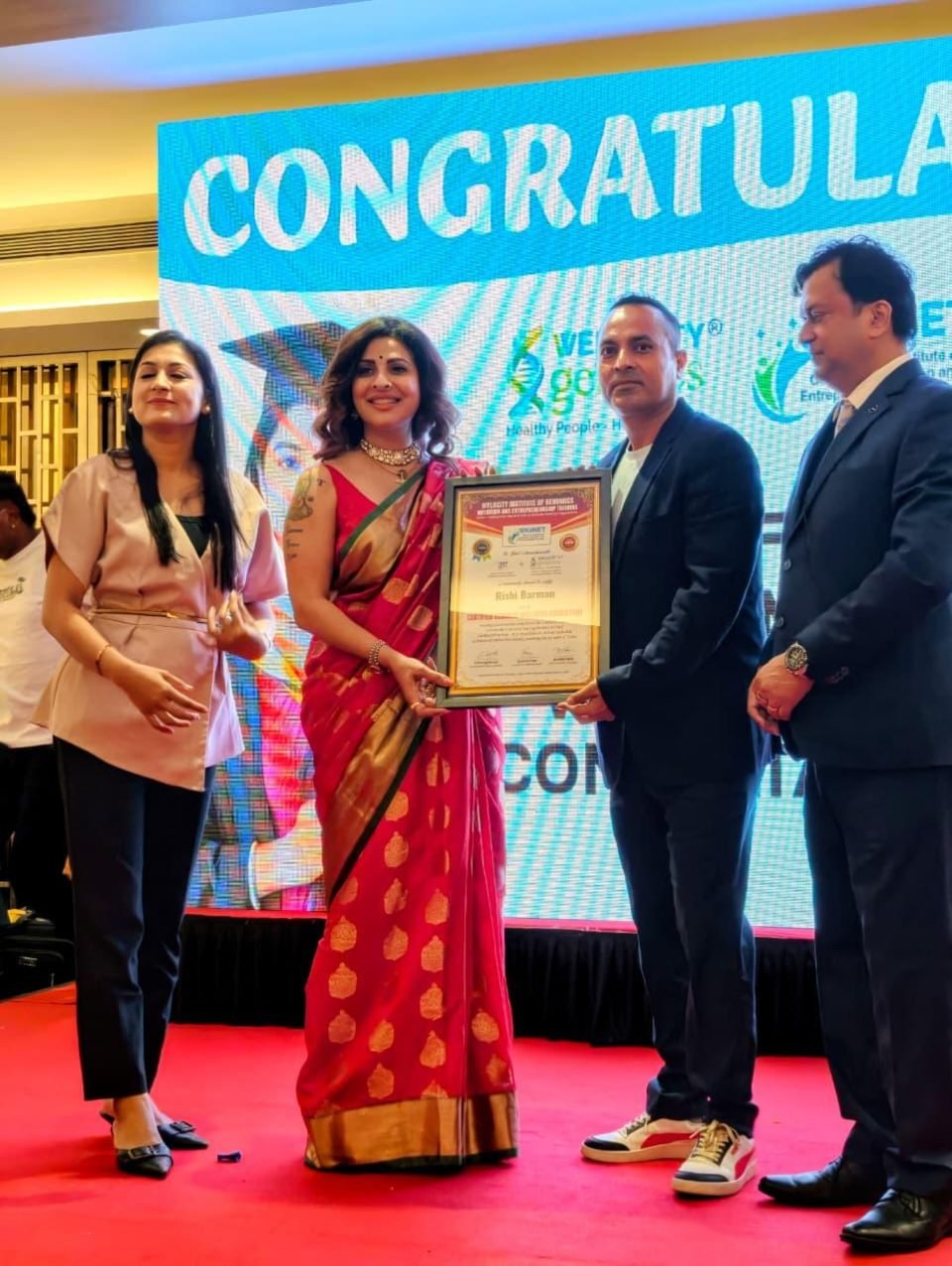 Rrishi Barman receiving a framed certificate on stage at the Welocity Institute of Genomics